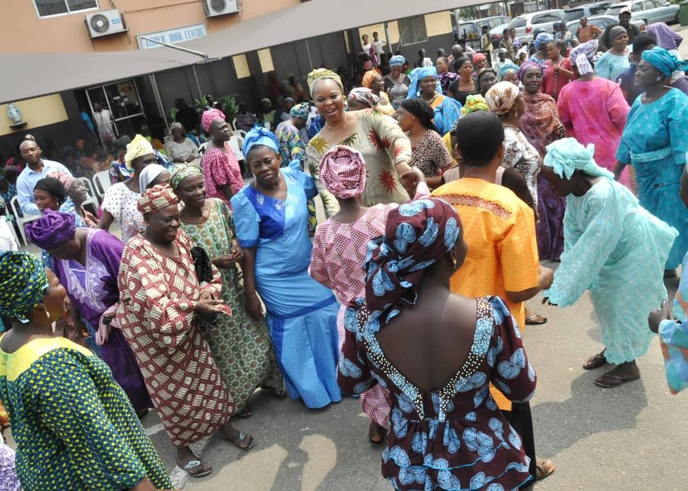 Elderly women and community members dancing together outdoors