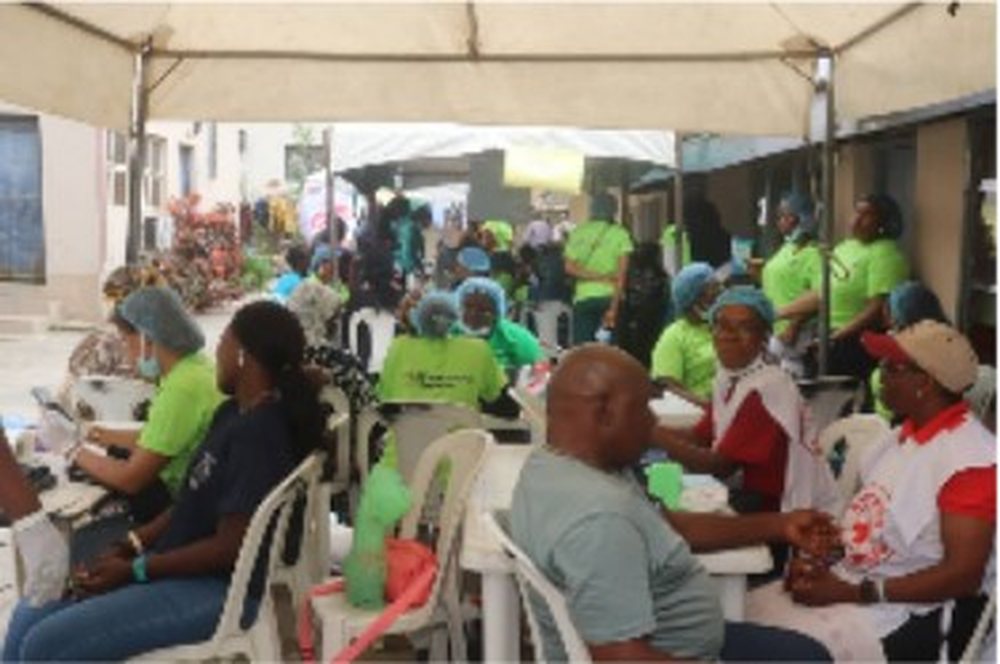 A volunteer attending to an elderly man at a medical outreach table