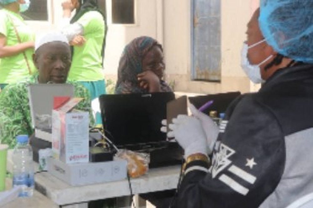 Two elderly women being attended to by a health volunteer